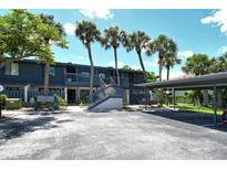 Inviting exterior of a blue condo building with palm trees and covered parking at 7214 Cloister Dr # 7214, Sarasota, FL 34231