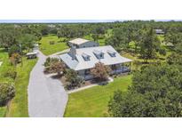 An aerial view of a charming single-story home with a metal roof, surrounded by lush greenery and landscaping at 7264 Spencer Parrish Rd, Parrish, FL 34219