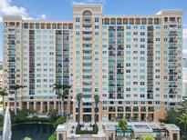 Luxury high-rise condo with a fountain, pool, and palms against a blue sky at 750 N Tamiami Trl # 1005, Sarasota, FL 34236
