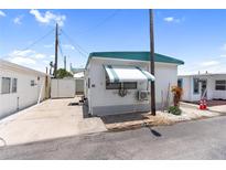 Charming mobile home featuring a teal awning, white lattice trim, and well-kept landscaping at 10315 Cortez W Rd # 60-4, Bradenton, FL 34210