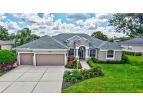 Beautiful single-story home with a three-car garage, manicured lawn, and colorful landscaping at 11250 Rivers Bluff Cir, Lakewood Ranch, FL 34202