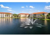 Scenic view of condo buildings surrounding a tranquil lake with a fountain under a blue sky at 150 L Pavia Blvd # 13, Venice, FL 34292