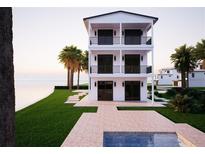 Beautiful, modern three-story home with multiple balconies overlooking a waterfront lawn at 312 Avenida Leona, Sarasota, FL 34242