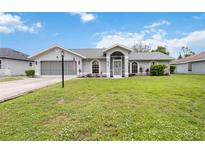 Charming single-story home featuring a well-manicured lawn, attached garage, and welcoming screened front entry at 4250 Winfall Ave, North Port, FL 34286