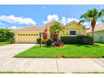 Charming yellow home featuring a tile roof, a well-manicured lawn, and vibrant landscaping at 6216 Donnington Ct, Sarasota, FL 34238