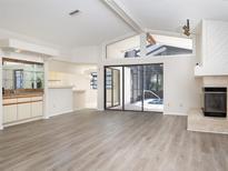Bright living room with vaulted ceilings, fireplace, bar, and sliding glass doors to the pool at 8260 Berkeley Manor Blvd, Spring Hill, FL 34606
