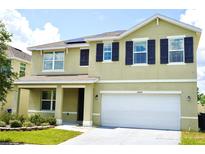 Two-story home featuring a two-car garage, dark shutters, and solar panels on the roof at 10019 Geese Trail Cir, Sun City Center, FL 33573
