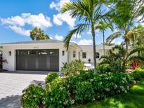 Beautiful exterior with lush tropical landscaping and an elegant black garage door at 1031 Contento St, Sarasota, FL 34242