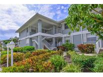 Condo exterior features nicely landscaped grounds and a light blue facade with white railings and shutters at 1319 Perico Point Cir, Bradenton, FL 34209