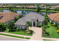 Stunning waterfront home with lush landscaping, tile roof, and brick paver driveway at 16628 Berwick Ter, Lakewood Ranch, FL 34202