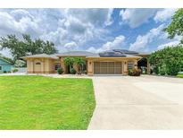 Beautiful single-Gathering home showcases lush green lawn, solar panels, and an extended covered driveway at 23136 Langdon Ave, Port Charlotte, FL 33954