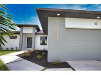 Modern home featuring a gray garage door, manicured landscaping, and stylish exterior lighting at 350 Bucknell Rd, Venice, FL 34293