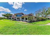 Well-maintained home featuring a lush green lawn, large windows and red trim against a bright, blue sky at 500 Park S Blvd # 97, Venice, FL 34285