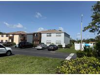 View of a two-story condominium building with parking, landscaping, and mailbox area under a sunny blue sky at 5026 Water Oak Dr # 114, Bradenton, FL 34207