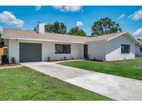 Charming single-story home with a well-manicured lawn, a gray garage door, and fresh landscaping at 5032 Barcelona Ave, Sarasota, FL 34235
