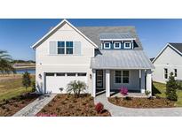 Charming two-story home featuring a metal roof, white siding, and manicured landscaping at 662 Maldives Trl, Sarasota, FL 34234