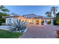Stunning exterior featuring a brick driveway, lush landscaping, and a light blue colored roof at 1530 Pine Bay Dr, Sarasota, FL 34231