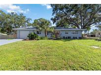 Charming single-story home with a lush lawn, mature trees, and beautifully landscaped garden beds at 3011 Bougainvillea St, Sarasota, FL 34239