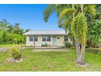 Charming single-story home featuring a metal roof, inviting front yard with mature palm trees and lush lawn at 3511 39Th E St, Palmetto, FL 34221