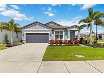 Charming single-story home with a manicured lawn, palm trees, and a gray two car garage at 3602 Quiet Dr, Sarasota, FL 34240