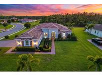 Stunning single-story home featuring a well-manicured lawn and beautiful landscaping at sunset at 408 166Th E St, Bradenton, FL 34212