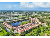 Beautiful aerial view of townhomes with a central lake featuring a fountain and lush landscaping at 4210 Vicenza Dr # D25, Venice, FL 34293