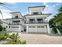 Modern three-story home showcasing balconies, a three-car garage, and a brick driveway at 455 Cleveland Dr, Sarasota, FL 34236