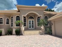 Stunning home featuring a beautiful arched entryway, well-manicured landscaping, and a brick paver driveway at 624 Mourning Dove Dr, Sarasota, FL 34236