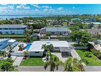Stunning aerial view of waterfront home with pool and canal access in a lush, tropical neighborhood with ocean views at 726 Jungle Queen Way, Longboat Key, FL 34228