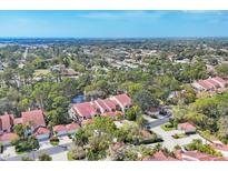 Expansive aerial view of community with mature trees, serene pond, and well-maintained red tile roofs at 7674 Fairway Woods Dr # 1605, Sarasota, FL 34238