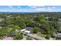 Expansive aerial view of a home surrounded by lush greenery with a city skyline and bay in the distance at 1857 Siesta Dr, Sarasota, FL 34239