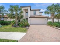 Beautiful two-story home featuring a brick driveway, attached garage, and well-manicured lawn with mature landscaping at 19369 Nearpoint Dr, Venice, FL 34292