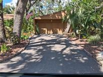 Long driveway leading to a two-car garage, surrounded by lush greenery at 2411 Quail Ct, Bradenton, FL 34209