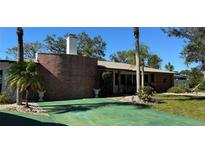Charming single-story home with a brick accent wall, mature landscaping, and a green driveway at 4158 Prudence Dr, Sarasota, FL 34235