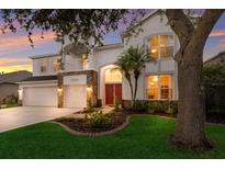 Elegant two-story home with a red front door, stone accents, manicured lawn, and three-car garage at 4410 67Th Avenue E Cir, Sarasota, FL 34243