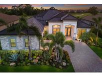 Stunning single-Gathering home showcasing lush tropical landscaping and a paver driveway at 5804 Mulligan Way, Lakewood Ranch, FL 34211