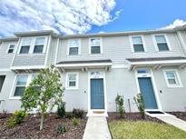 Townhome exterior featuring a blue door, manicured lawn, and neutral siding at 6253 Whetstone Ct, Palmetto, FL 34221