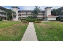 Well-maintained condo building with lush landscaping, palm trees, and a welcoming walkway at 6507 Stone River Rd # 302, Bradenton, FL 34203