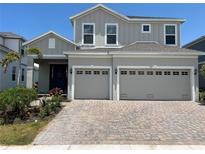 Charming two-story home with gray siding, dual garage and a brick paver driveway at 931 Signet Dr, Apollo Beach, FL 33572