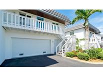 Charming two-story home featuring a garage, white picket balcony, and staircase, surrounded by lush landscaping and a palm tree at 10311 Waterbird Way, Bradenton, FL 34209