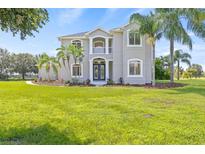 Stunning two-story home boasting lush landscaping, mature palms, and a well-manicured lawn on a sunny day at 18307 White Fang Ct, Parrish, FL 34219