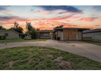Exterior view of a single-story home with a large driveway and partially boarded-up garage at sunset at 268 Alsace Ave, Venice, FL 34293