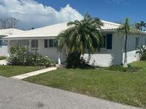 Charming white home featuring lush landscaping and vibrant plants creating inviting curb appeal at 675 El Centro # 675, Longboat Key, FL 34228