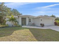Charming one-story home with a well-manicured lawn, complemented by a beautiful palm tree and a cozy seating area near the entryway at 8755 Dolomite Ave, North Port, FL 34287