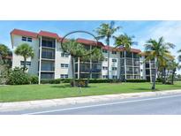 A well-maintained condo building with balconies, red roof, lush landscaping, and palm trees at 925 Beach Rd # 408, Sarasota, FL 34242