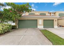 Townhouse with two-car garage, green doors, and lush landscaping framing the driveway and facade at 2303 28Th E Ave, Palmetto, FL 34221