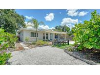 Charming home featuring a gravel yard, patio furniture, and tasteful landscaping under a sunny, partly cloudy sky at 809 40Th St, Sarasota, FL 34234