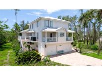 Charming two-story coastal home with a white exterior, multiple balconies, and a spacious driveway at 9403 9Th Nw Ave, Bradenton, FL 34209