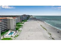 Expansive beachside condos, showcasing pristine sandy shoreline and turquoise ocean views under a partly cloudy sky at 1150 Tarpon Center Dr # 1-C 103, Venice, FL 34285