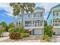 Charming blue two-story beach house with a brick driveway and tropical landscaping at 202 75Th St, Holmes Beach, FL 34217